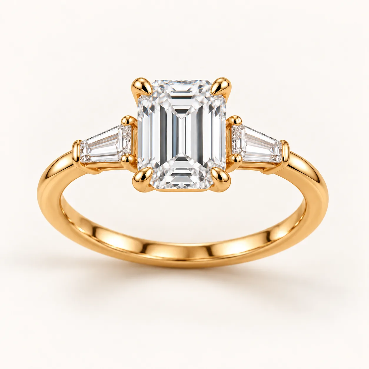 Emerald-cut diamond three-stone ring with tapered baguettes in yellow gold